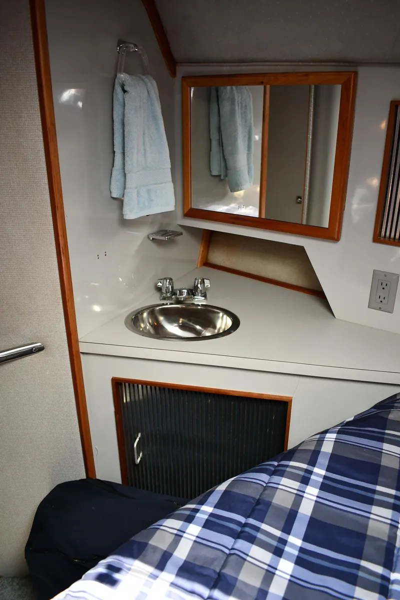 Slide: The Image of 1989 Sea Ray 390 Express Cruiser cabin with sink, mirror, and plaid bedding. - 37