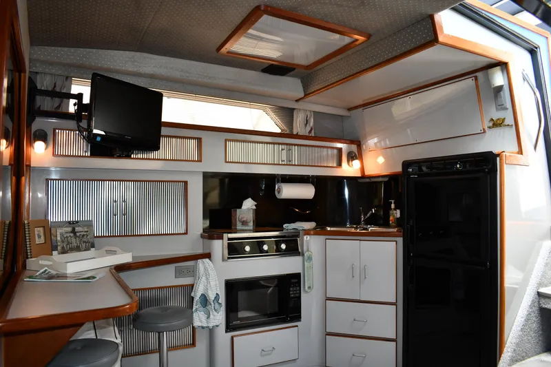 Slide: The Image of 1989 Sea Ray 390 Express Cruiser interior with kitchen, TV, and seating area. - 45