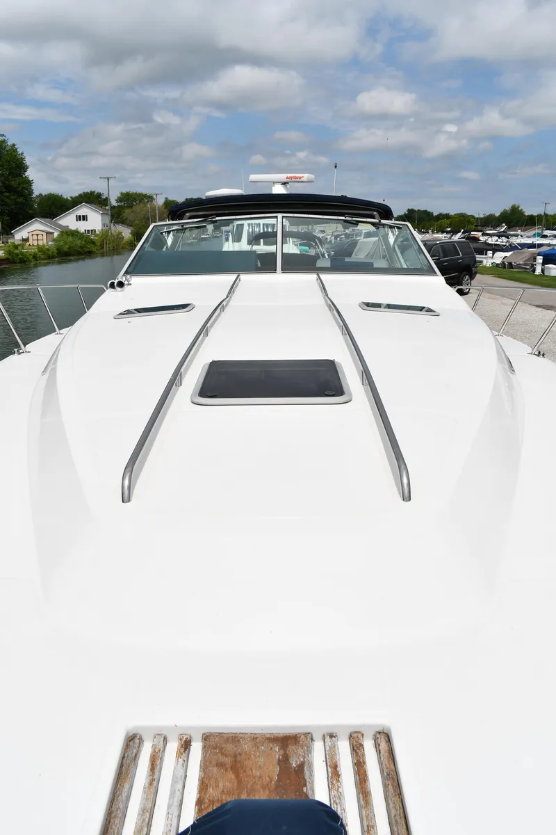 Slide: The Image of 1989 Sea Ray 390 Express Cruiser, sleek white deck, docked under a partly cloudy sky. - 8