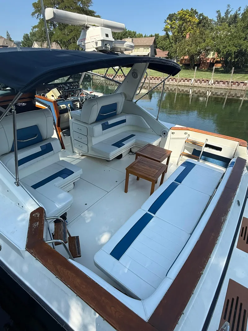 Slide: The Image of 1989 Sea Ray 390 Express Cruiser with spacious seating and wooden accents docked by a canal. - 9