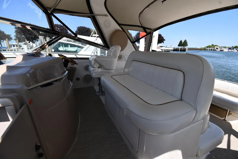 Slide: The Image of 1997 Sea Ray 400 Sundancer interior with white seating and helm, overlooking marina. - 19