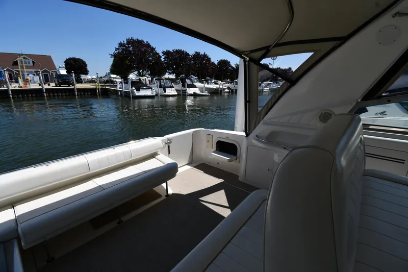 Slide: The Image of 1997 Sea Ray 400 Sundancer interior with marina view, featuring white seating and open deck. - 26