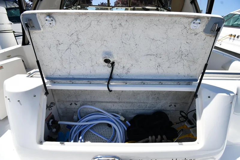Slide: The Image of Open storage compartment on a 1997 Sea Ray 400 Sundancer boat, containing hoses and ropes. - 29