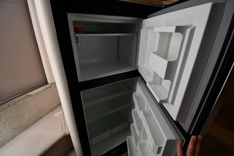 Slide: The Image of Open refrigerator inside 1997 Sea Ray 400 Sundancer yacht, showing empty shelves and compartments. - 49