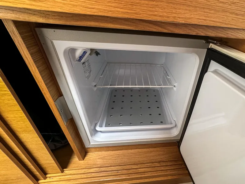 Slide: The Image of Open mini fridge inside 2024 De Antonio Yachts D28 Cruiser, featuring wooden cabinetry. - 10