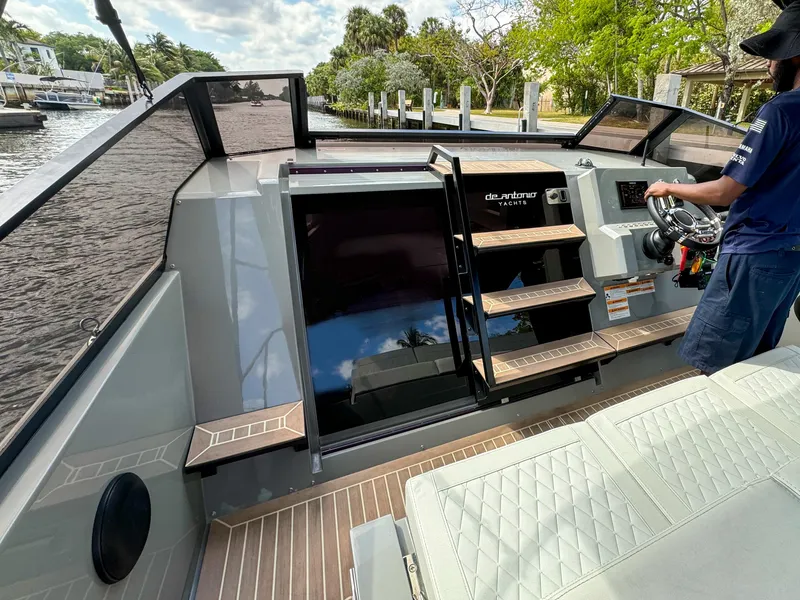 Slide: The Image of 2024 De Antonio Yachts D28 Cruiser interior with helm, seating, and wooden steps. - 5