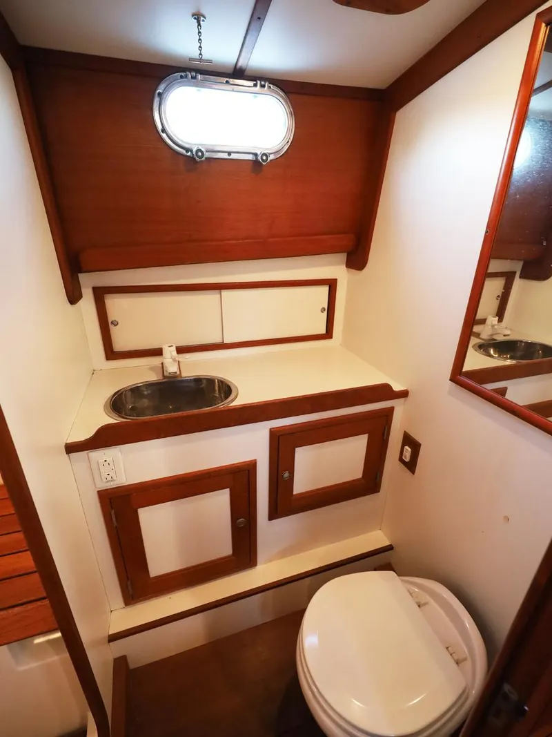 Slide: The Image of Wood-accented boat bathroom with sink, mirror, and porthole window, Able 44, 1995 model. - 16