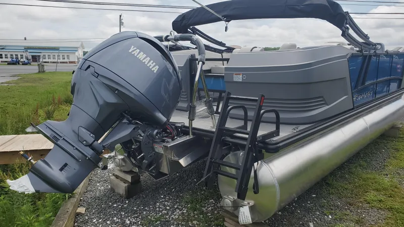 Slide: The Image of 2025 Starcraft GX 22 R DH Sport pontoon boat with Yamaha outboard motor, parked on gravel. - 2