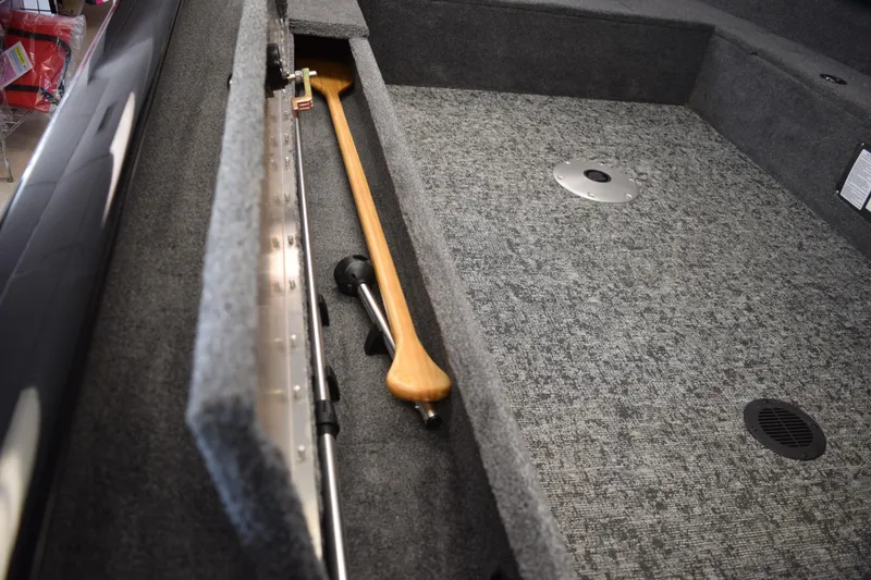 Slide: The Image of 2025 Tracker Suoer Guide V16 T boat interior with storage compartment and wooden paddle. - 7