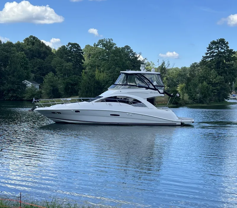 Slide: The Image of 2008 Sea Ray 47DB yacht on a serene lake with lush green trees. - 0