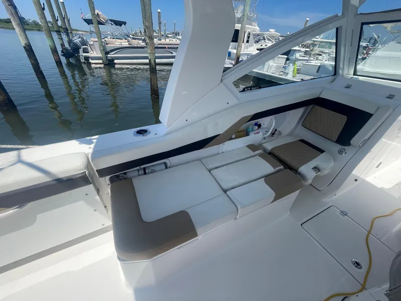 Slide: The Image of 2021 Edgewater 262 CX boat interior with cushioned seating at a marina. - 24