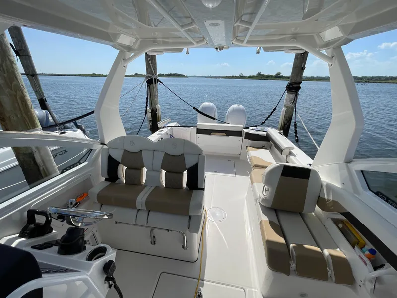 Slide: The Image of 2021 Edgewater 262 CX boat interior with seating, docked on calm water. - 25