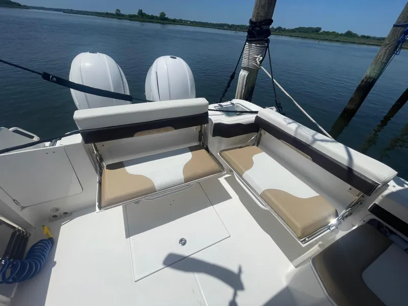 Slide: The Image of 2021 Edgewater 262 CX boat interior with seating and twin engines, docked by calm waters. - 29