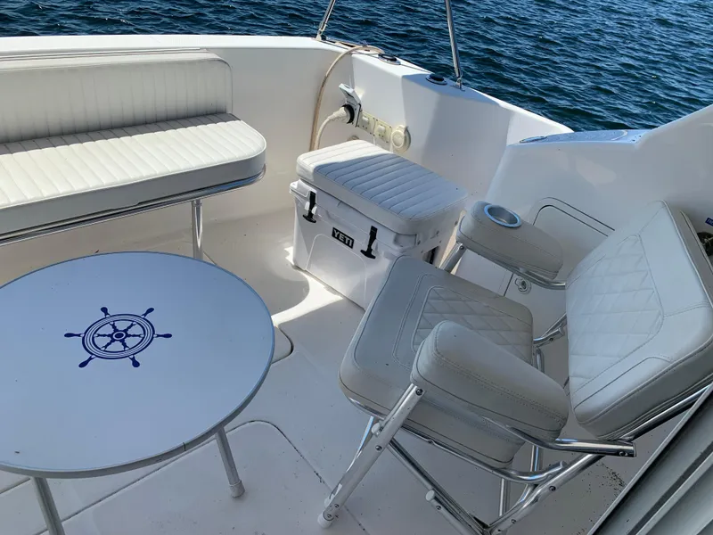 Slide: The Image of 2012 Silverton 33 Sport Coupe boat interior with white seating and nautical-themed table. - 11