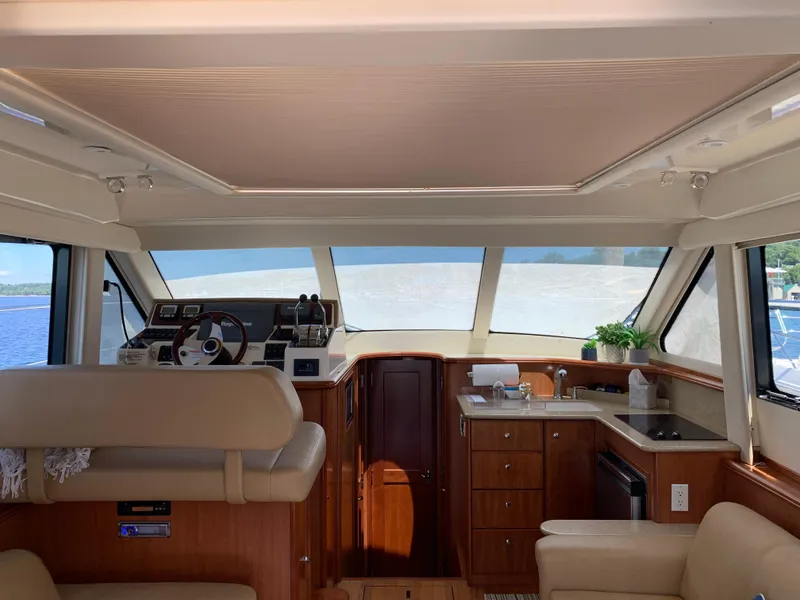 Slide: The Image of Interior of 2012 Silverton 33 Sport Coupe yacht with helm, kitchenette, and seating area. - 12