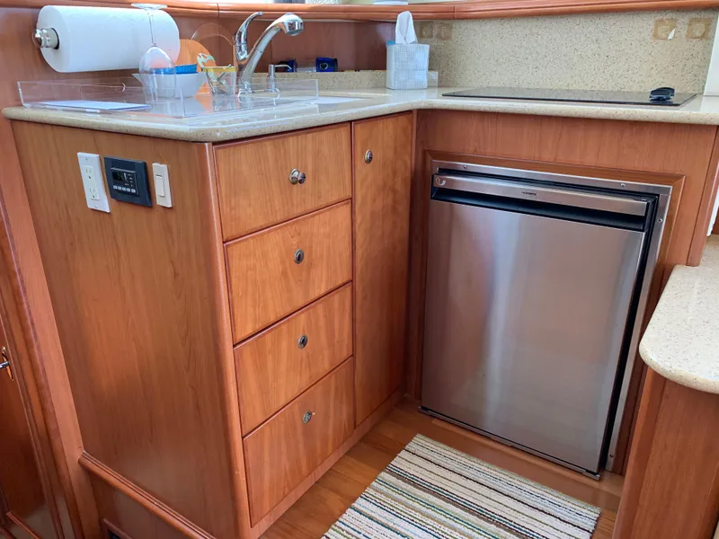 Slide: The Image of 2012 Silverton 33 Sport Coupe kitchen with wood cabinetry, stainless steel fridge, and countertop sink. - 20