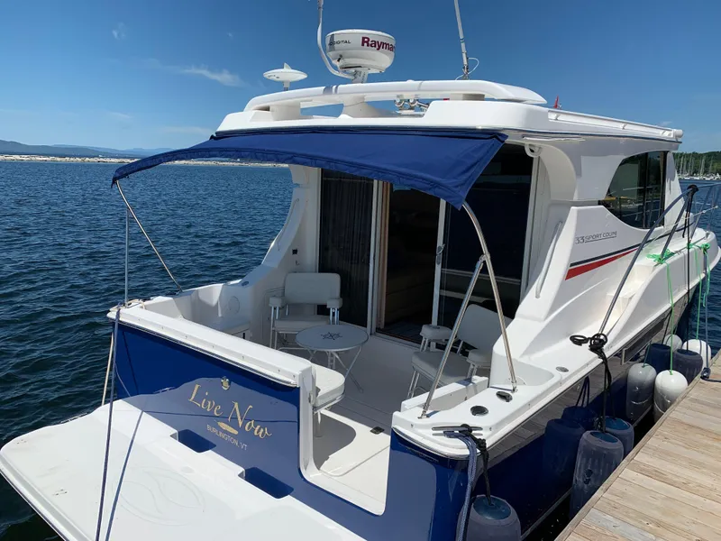 Slide: The Image of 2012 Silverton 33 Sport Coupe docked, featuring a blue canopy and spacious deck. - 8