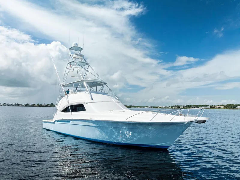 Slide: The Image of 2004 Bertram 570 yacht on calm water under a partly cloudy sky. - 2