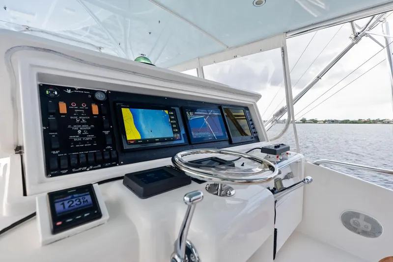 Slide: The Image of Control panel of a 2004 Bertram 570 yacht with navigation screens and steering wheel. - 22