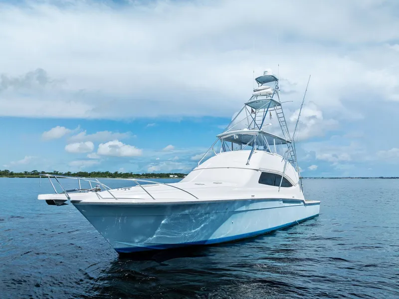 Slide: The Image of 2004 Bertram 570 yacht on calm blue waters under a partly cloudy sky. - 3