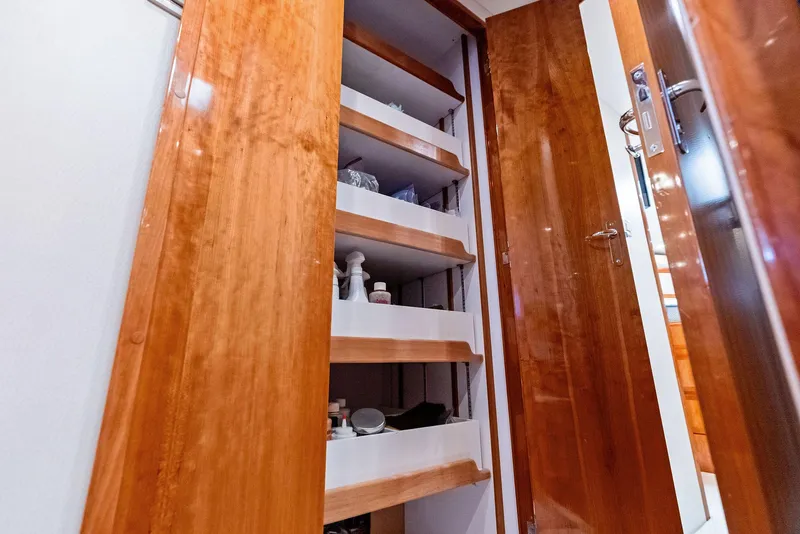 Slide: The Image of Wooden storage shelves inside a 2004 Bertram 570 yacht, featuring various items neatly organized. - 39