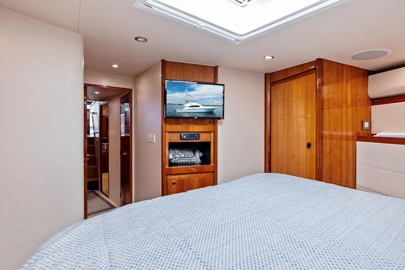 Slide: The Image of Luxurious 2004 Bertram 570 yacht bedroom with TV and wooden interior. - 41