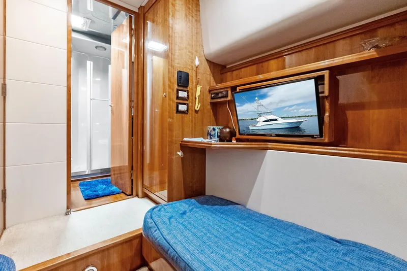 Slide: The Image of Interior of 2004 Bertram 570 yacht with wooden paneling and blue bedding. - 44