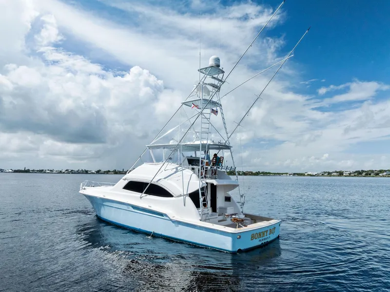Slide: The Image of 2004 Bertram 570 yacht on calm waters under a partly cloudy sky. - 6