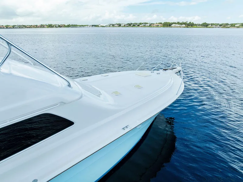 Slide: The Image of 2004 Bertram 570 yacht on calm water, showcasing sleek design and spacious deck. - 9