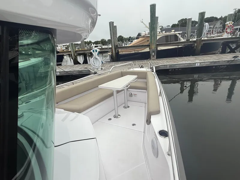 Slide: The Image of 2023 Axopar 28 CABIN boat with seating area and table, docked at marina. - 11