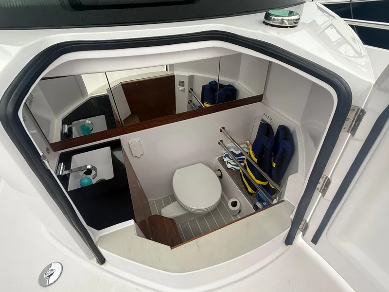 Slide: The Image of 2023 Axopar 28 CABIN boat interior with compact bathroom and storage. - 12