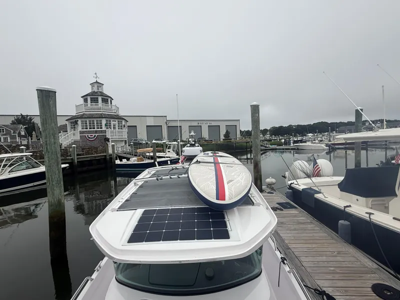 Slide: The Image of 2023 Axopar 28 CABIN docked with paddleboard on roof, marina background. - 13