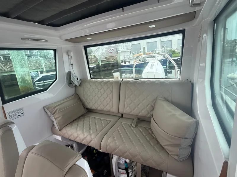 Slide: The Image of Interior of 2023 Axopar 28 CABIN with beige quilted seating and large windows. - 15