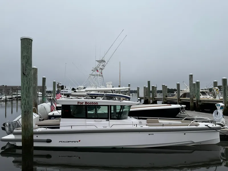 Slide: The Image of 2023 Axopar 28 CABIN boat docked in a marina on a cloudy day. - 3
