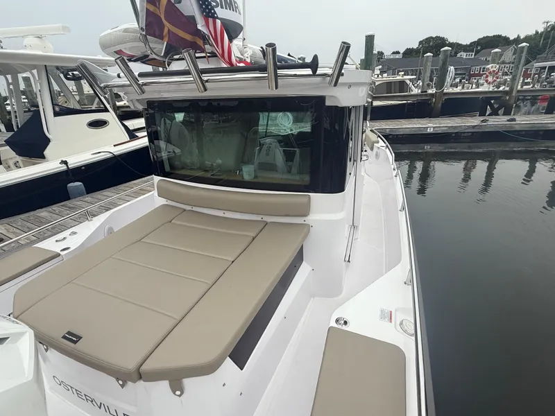 Slide: The Image of 2023 Axopar 28 CABIN boat docked, featuring beige seating and sleek design. - 6