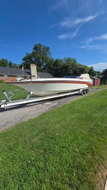 Slide: The Image of 1989 Fountain 36 Fever boat on trailer, parked in residential area, clear blue sky. - 2