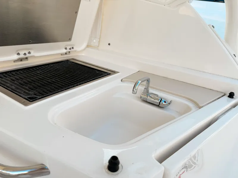 Slide: The Image of Pursuit DC 365 Dual Console 2022 boat sink and grill area, featuring sleek design. - 19
