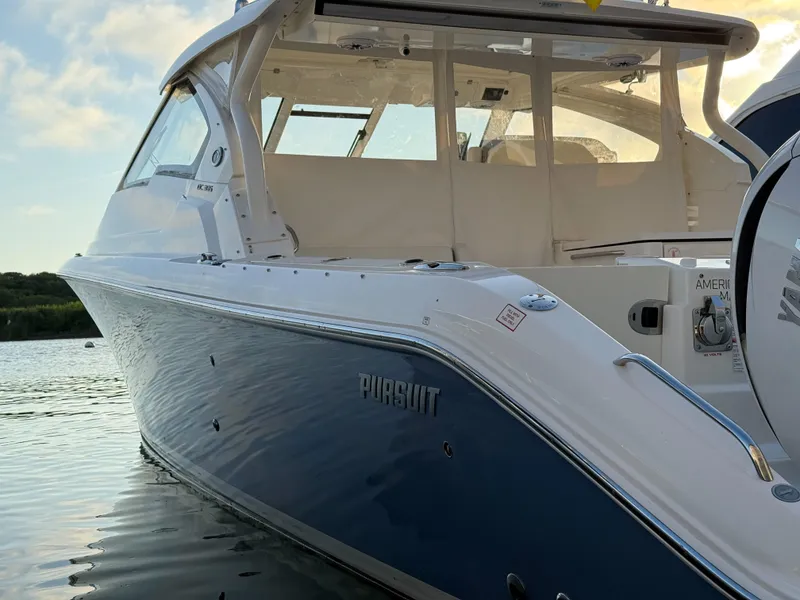 Slide: The Image of 2022 Pursuit DC 365 Dual Console boat on calm water at sunset. - 2