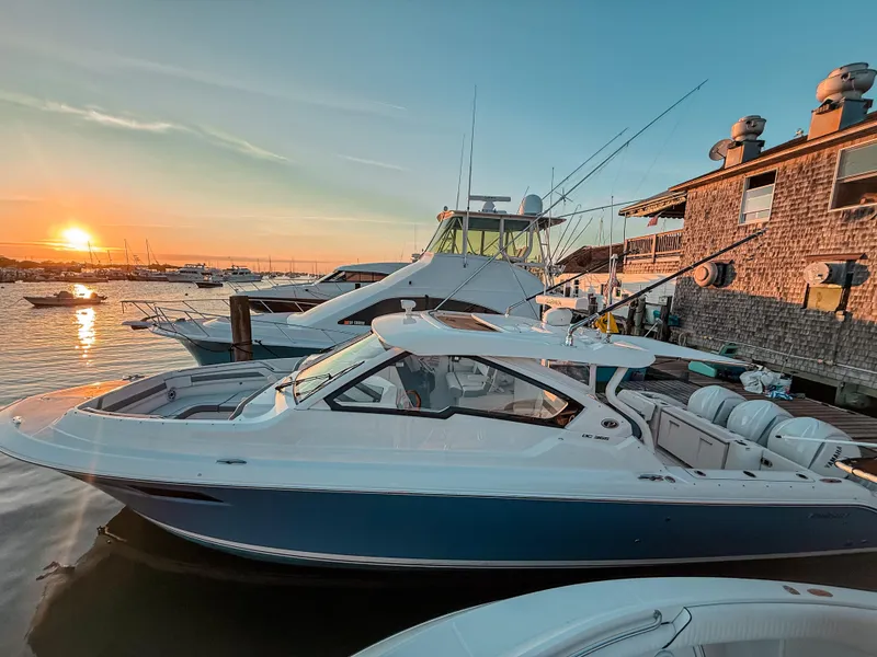Slide: The Image of 2022 Pursuit DC 365 Dual Console boat docked at sunset, with serene water and clear sky. - 3