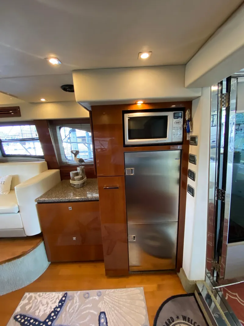 Slide: The Image of 2008 Sea Ray 47 Sedan Bridge interior with modern kitchen appliances and elegant wood finish. - 12