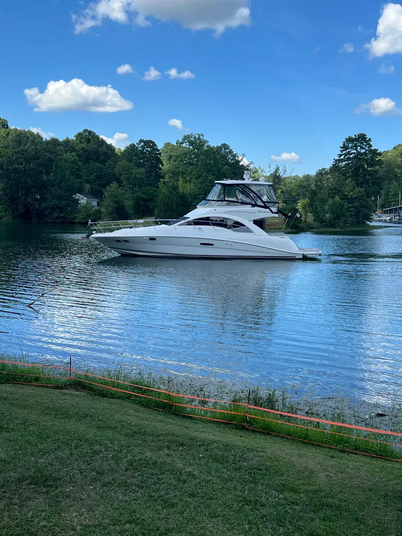 Slide: The Image of 2008 Sea Ray 47 Sedan Bridge yacht cruising on a serene lake under a blue sky. - 2