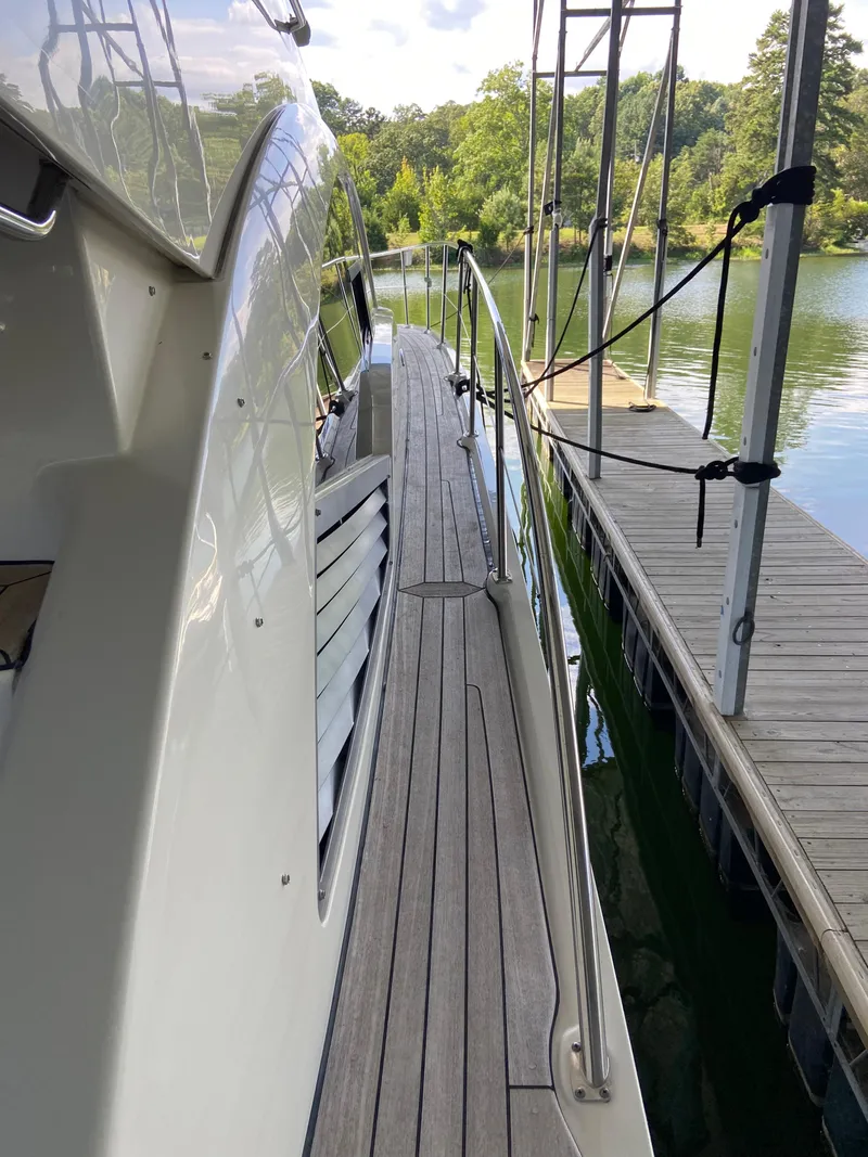 Slide: The Image of 2008 Sea Ray 47 Sedan Bridge yacht docked by a serene lake. - 33