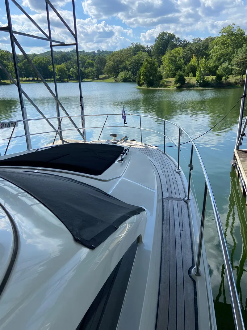 Slide: The Image of 2008 Sea Ray 47 Sedan Bridge yacht docked on a serene lake with lush greenery. - 34
