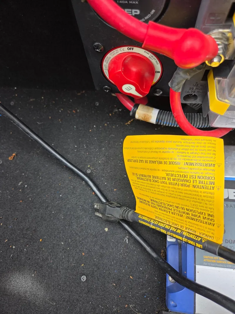 Slide: The Image of Close-up of Bennington QX 25 Sport 2020 battery compartment with cables and warning label. - 12