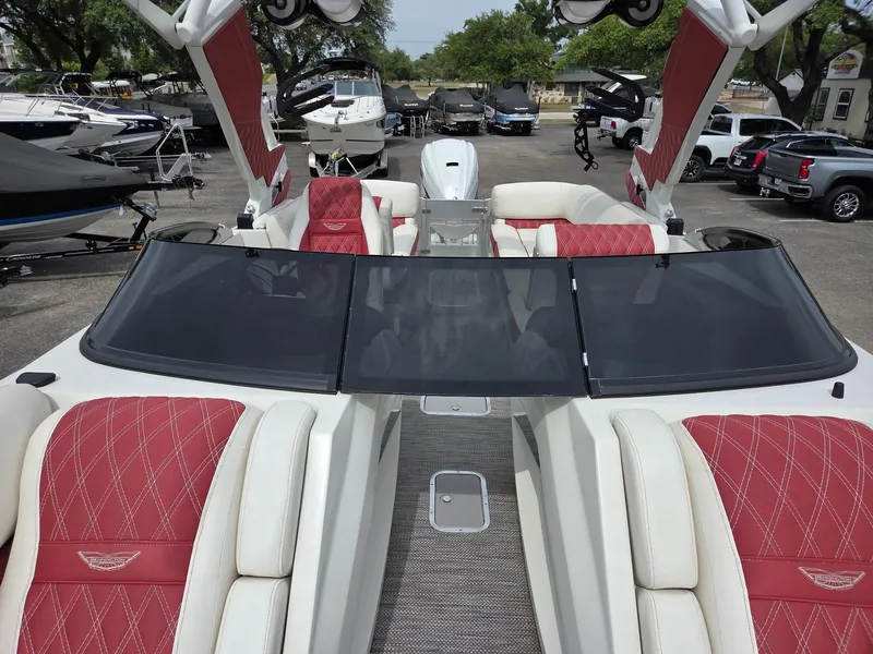 Slide: The Image of 2020 Bennington QX 25 Sport boat with red and white seating, docked among other boats. - 7