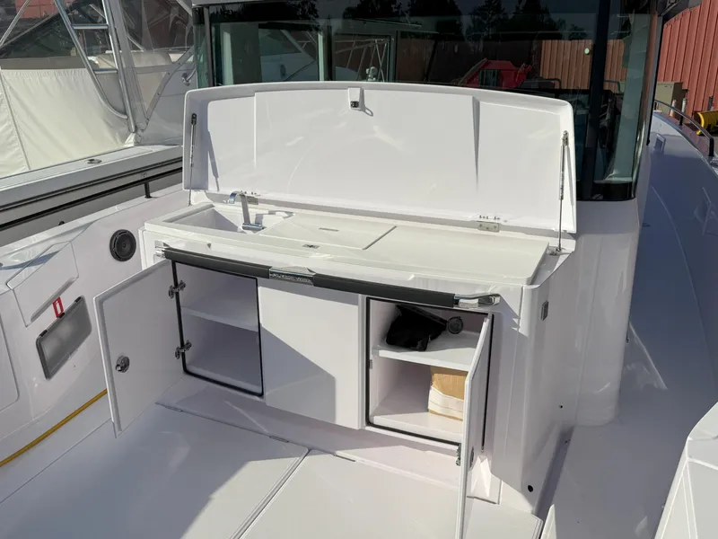 Slide: The Image of 2024 Axopar Cross Cabin storage compartment with drainage and blue valve. - 16