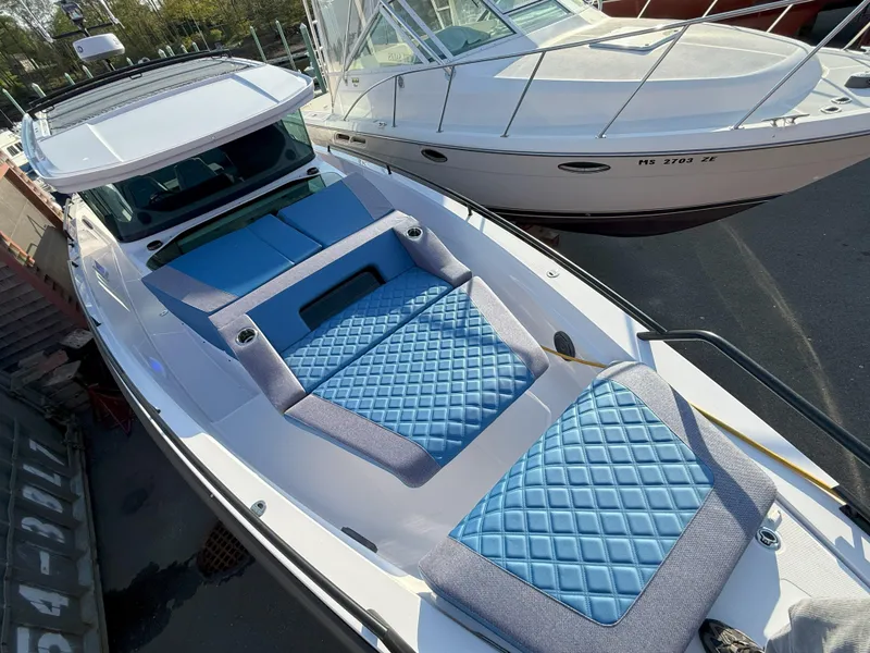 Slide: The Image of 2024 Axopar Cross Cabin boat with blue cushioned seating on deck. - 2