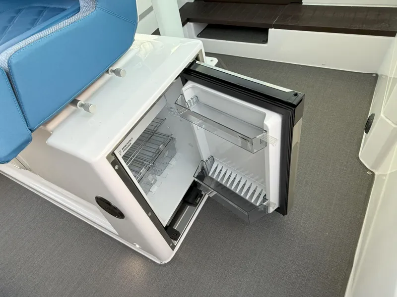 Slide: The Image of 2024 Axopar Cross Cabin interior with blue seating and open mini fridge. - 41