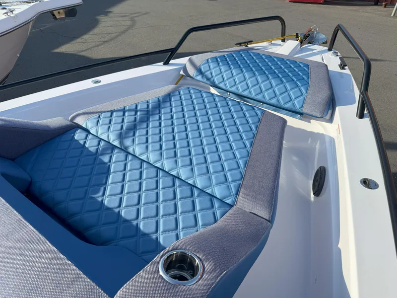 Slide: The Image of 2024 Axopar Cross Cabin boat with blue quilted seating, docked in a marina. - 5