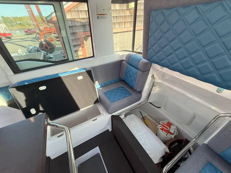 Slide: The Image of 2024 Axopar Cross Cabin interior with blue and gray seating, modern design, and ample windows. - 39